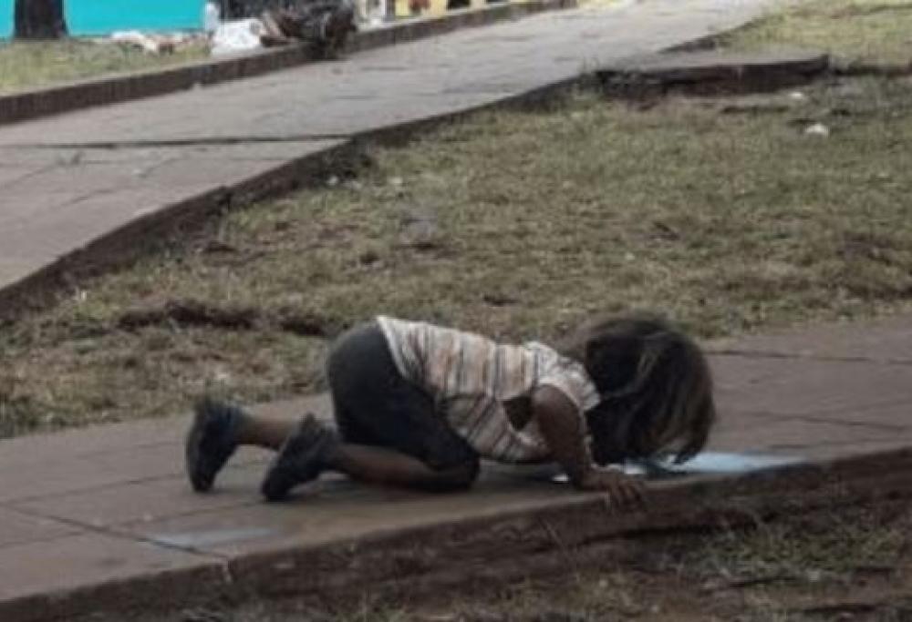 Foto shock: una bambina si disseta bevendo da una pozzanghera 