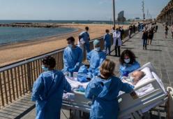 Infermieri portano sul Lungomare di Barcellona il paziente guarito dal Covid